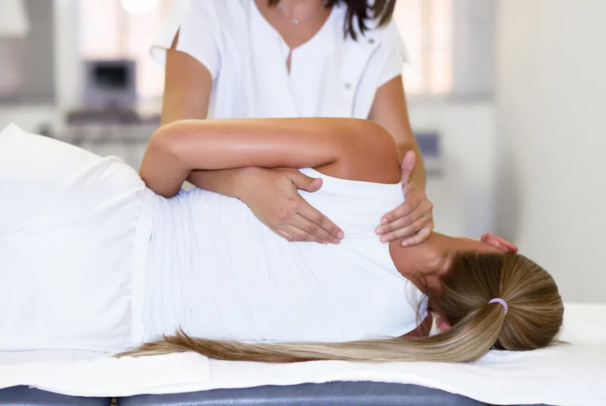 Physiotherapeutin behandelt Schulter einer Patientin